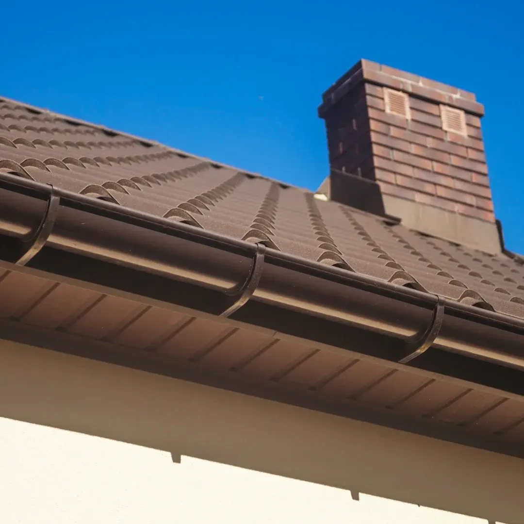 Brown roof with a brick chimney and blue sky above