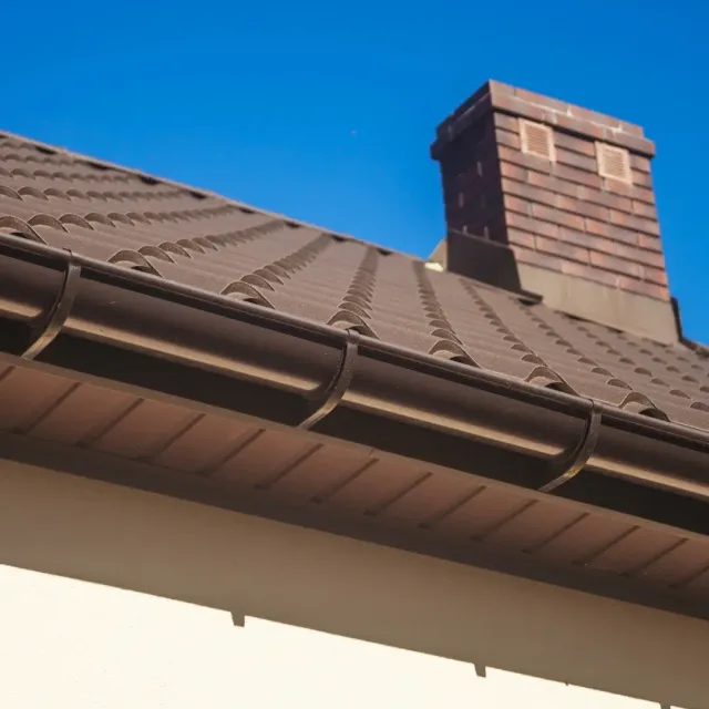Brown roof with a brick chimney and blue sky above