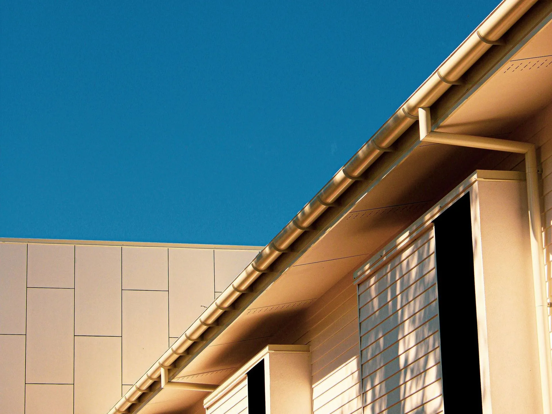 Modern building facade with beige panels, glass-block windows, and a blue sky background