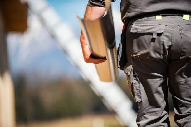 A man is carrying a gutter in his hand while walking.